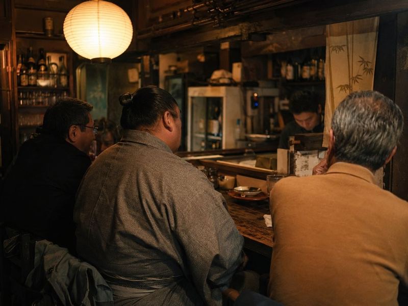 A sumo wrestler sharing drinks with guests at an Asakusa izakaya