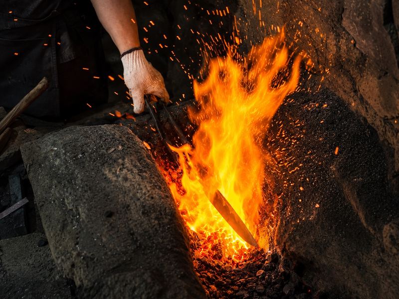 A master bladesmith forging a kitchen knife at a traditional Japanese smithy